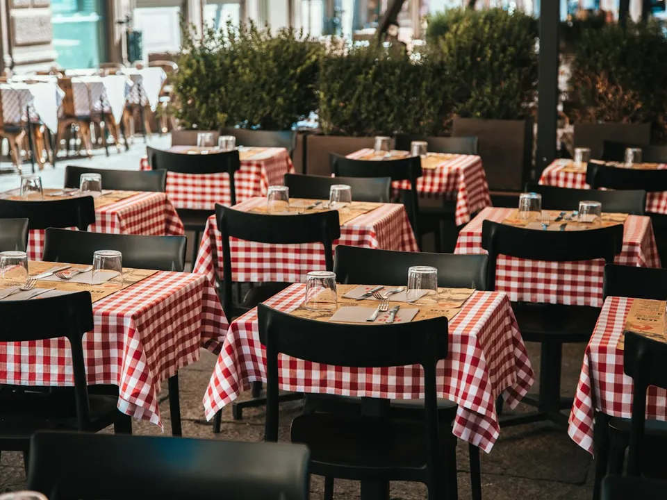 Mesas puestas en la terraza, con manteles de cuadros y copas de vino