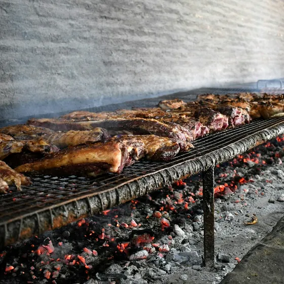 Parrilla de asador con costillas y cortes de carne sobre brasas encendidas