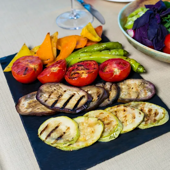 Tomates, pimientos, berenjena y calabacín asados a la brasa sobre una tabla